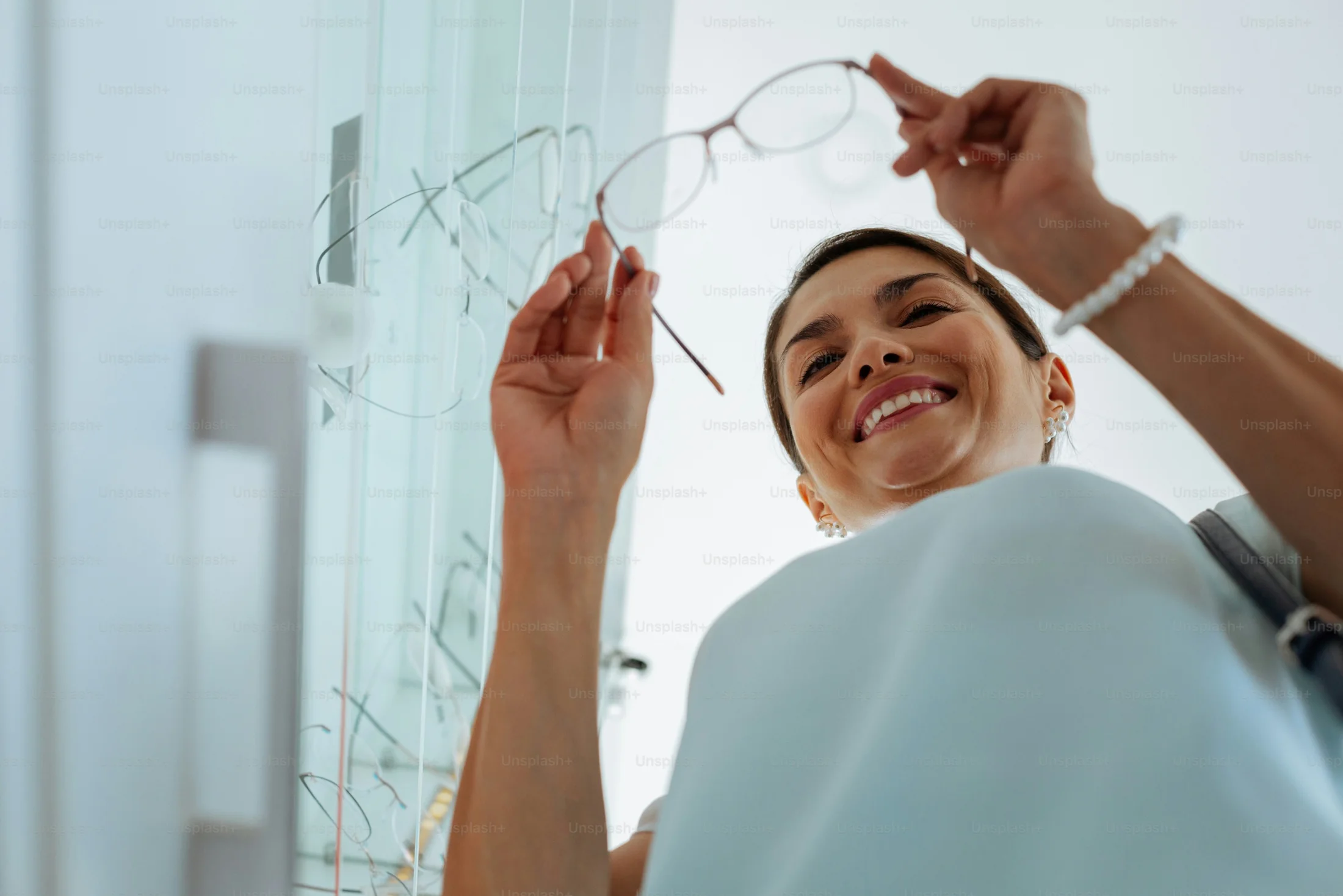Una cliente sorridente prova un paio di occhiali in un negozio di ottica